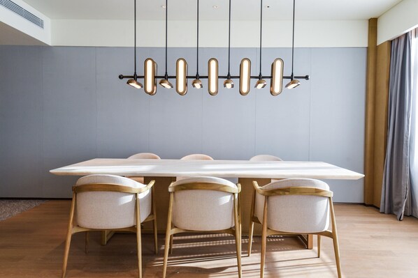 Un comedor moderno con una mesa larga, cuatro sillas y una lámpara colgante original.