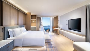 A modern hotel room with a large bed, a TV, a desk, and a view of the mountains. - Crowne Plaza Beijing Badaling (Yanqing)