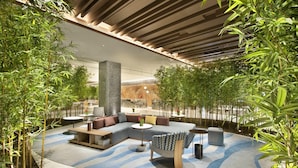A modern lounge area with a curved seating arrangement, a central pillar, and surrounding greenery. - Crowne Plaza Beijing Badaling (Yanqing)