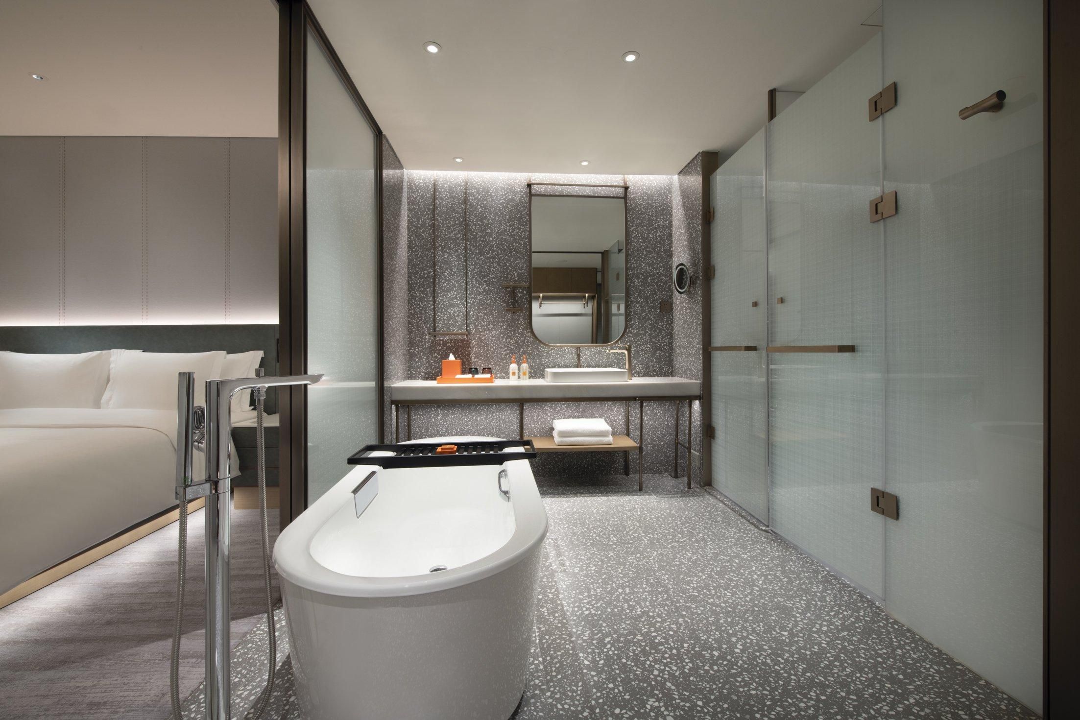A modern bathroom with a freestanding bathtub, a large mirror, and a glass shower enclosure.