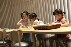 A group of children engaged in an activity at a table with chairs around it.
