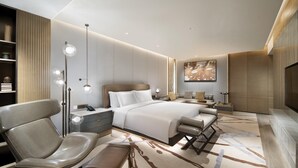 A modern hotel room with a large bed, a seating area with a chair and bench, a bedside table, a floor lamp, and a large artwork on the wall. - Crowne Plaza Beijing Badaling (Yanqing)