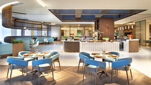 A modern hotel lobby with a central seating area, a staircase, and a reception desk. - Crowne Plaza Beijing Badaling (Yanqing)