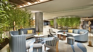 A modern lobby with seating areas, a central pillar, and indoor plants. - Crowne Plaza Beijing Badaling (Yanqing)