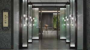 A modern entrance with frosted glass panels, hanging spherical lights, and a central decorative vase. - Crowne Plaza Beijing Badaling (Yanqing)