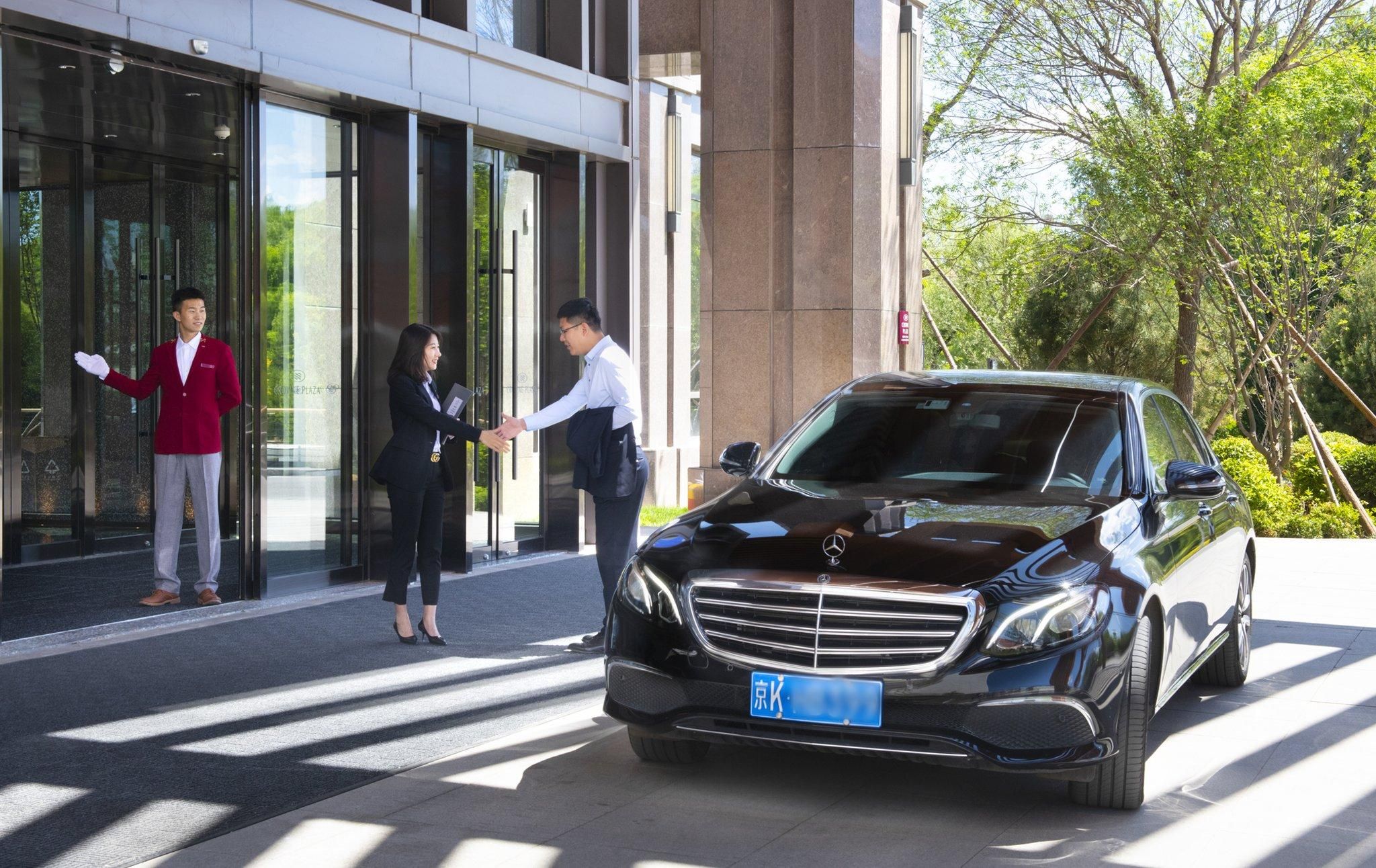 A black car parked in front of a building with glass doors.