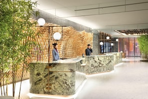 Un área de recepción moderna con detalles decorativos de bambú, mostradores de mármol y un diseño limpio y espacioso.