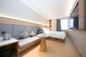 Ein modernes Hotelzimmer mit Bett, Sofa, kleinem Tisch und einer Kaffeemaschine.