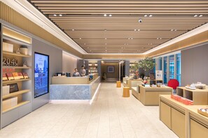 Un moderno vestíbulo de hotel con un mostrador de recepción, una pantalla digital y una librería.