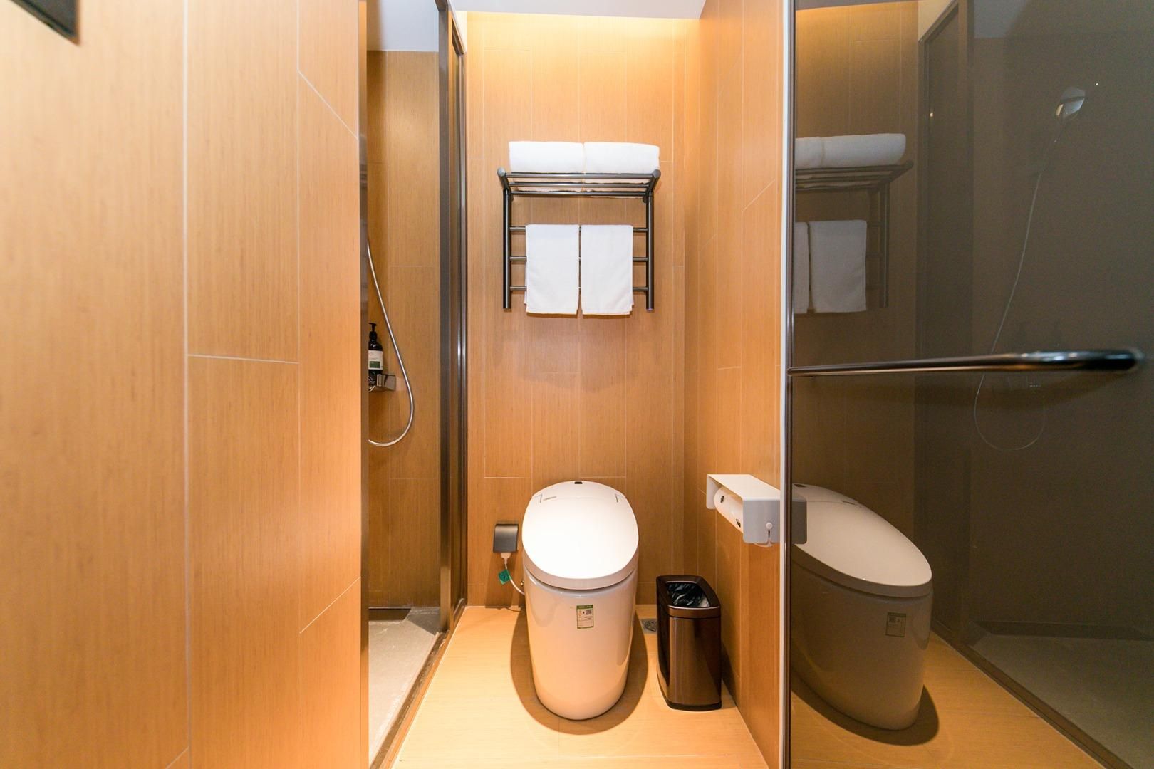 A compact bathroom with a toilet, bidet, and shower stall.