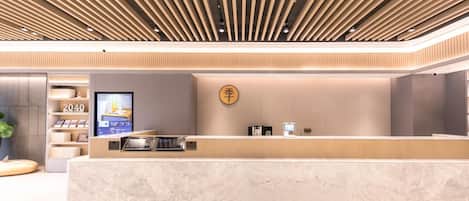 A modern reception desk with a digital screen, a cash register, and a wall-mounted sign.