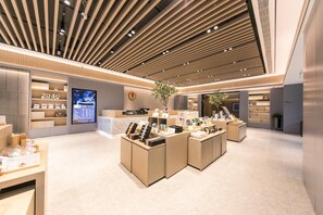 Interior moderno de una librería con un área de exhibición central, una pantalla digital y un mostrador de recepción.