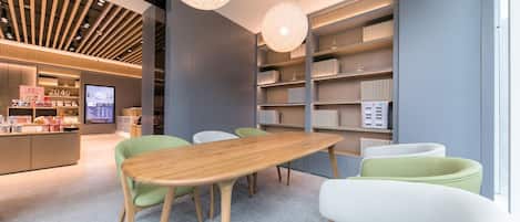 A modern interior with a wooden table, green and white chairs, and a bookshelf.