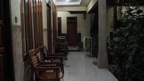 A corridor with wooden benches, a tiled floor, and a wall with greenery. - Sagita Bungalow by Zuzu (Gili Trawangan)