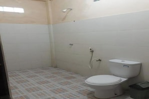 A small, tiled bathroom with a toilet, shower, and a tiled floor.