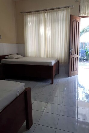 A room with two wooden beds, a curtain, and a door leading outside. - Sagita Bungalow by Zuzu (Gili Trawangan)