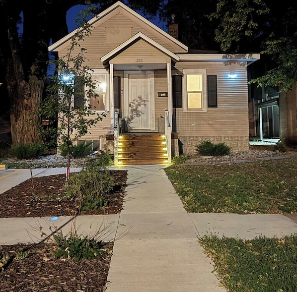 A two-story house with a front porch, a visible number '211' on the door, and a well-lit entrance.
