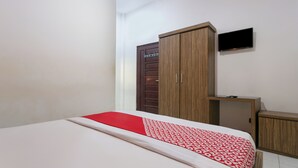 Un dormitorio con cama, armario, televisor y escritorio pequeño.