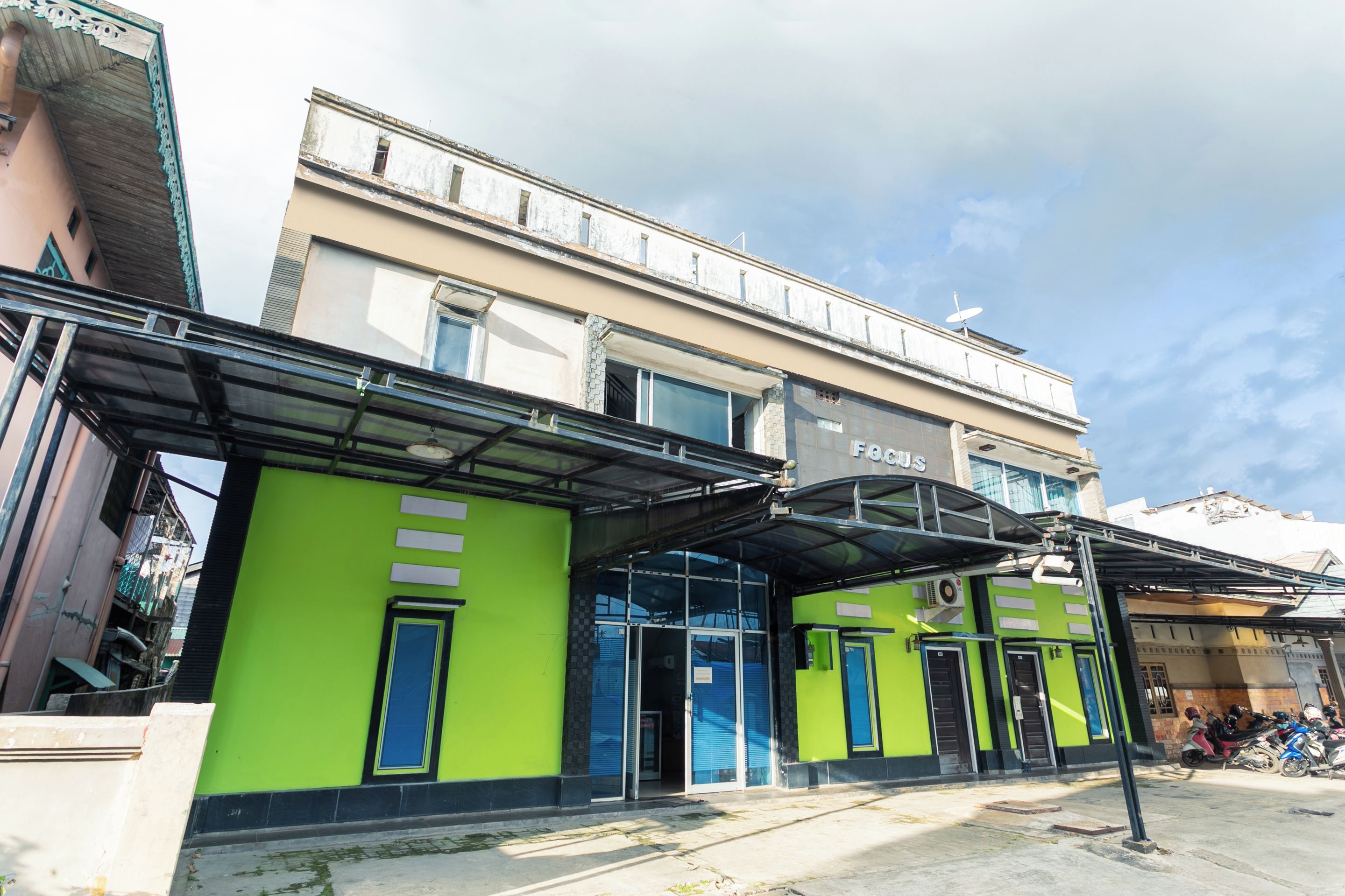 A building with a green facade, a covered entrance, and a satellite dish on the roof.