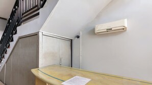 Habitación de hotel con mostrador de mármol, unidad de aire acondicionado blanca, una escalera y una puerta.