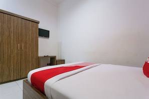 Un dormitorio con un armario de madera, una mesita de noche y una cama con colcha roja y blanca.