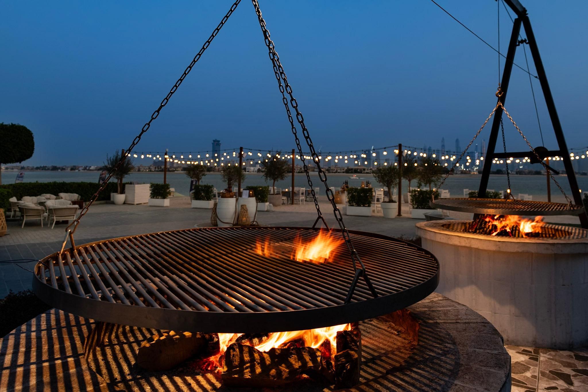 An outdoor grill area with a view of a bridge and water in the background.