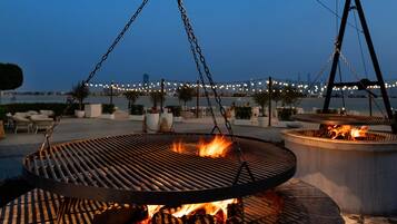An outdoor grill area with a view of a bridge and water in the background.