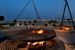 An outdoor grill area with a view of a bridge and water in the background. - Th8 Palm Dubai Beach Resort Vignette Collection (Dubai)