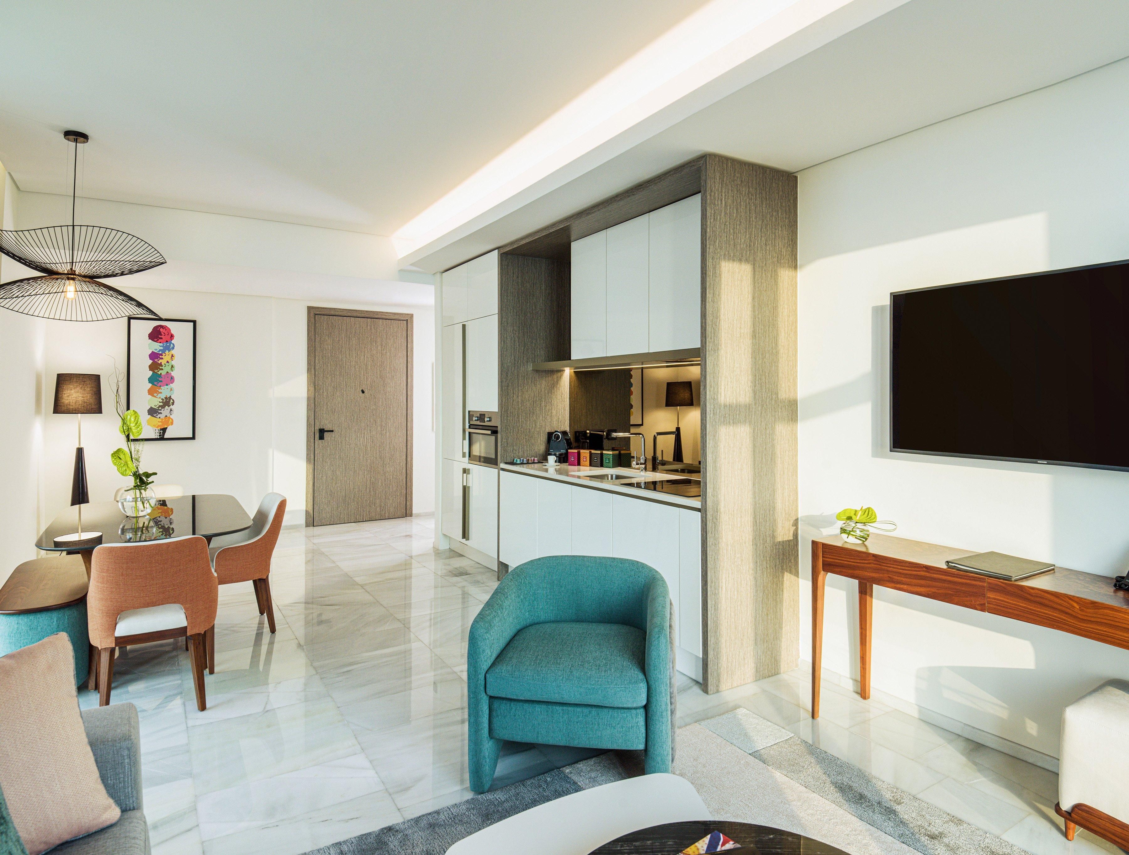 A modern living room with a dining area, a kitchen, and a TV.