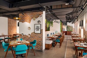 A restaurant with brick walls, wooden tables, teal chairs, and a menu stand. - Th8 Palm Dubai Beach Resort Vignette Collection (Dubai)