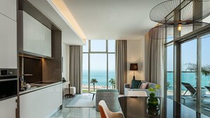 Una cocina moderna con horno empotrado, un comedor con mesa de vidrio y vista a la playa.