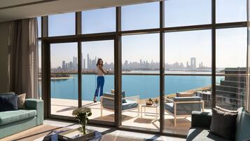 A spacious living room with a large window overlooking a city skyline and a body of water.