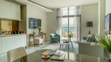 A modern living room with a dining area, a sofa, a TV, and a view of the city.