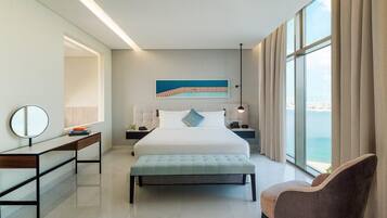 Habitación de hotel moderna con una cama grande, un escritorio, una silla y vista al mar.
