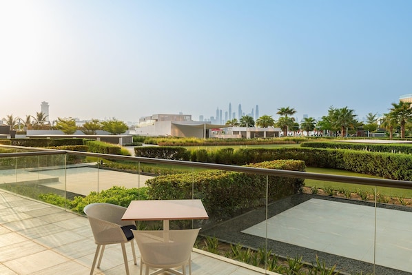 A rooftop terrace with a table and chairs, a view of the city skyline, and landscaped gardens. - Th8 Palm Dubai Beach Resort Vignette Collection (Dubai)