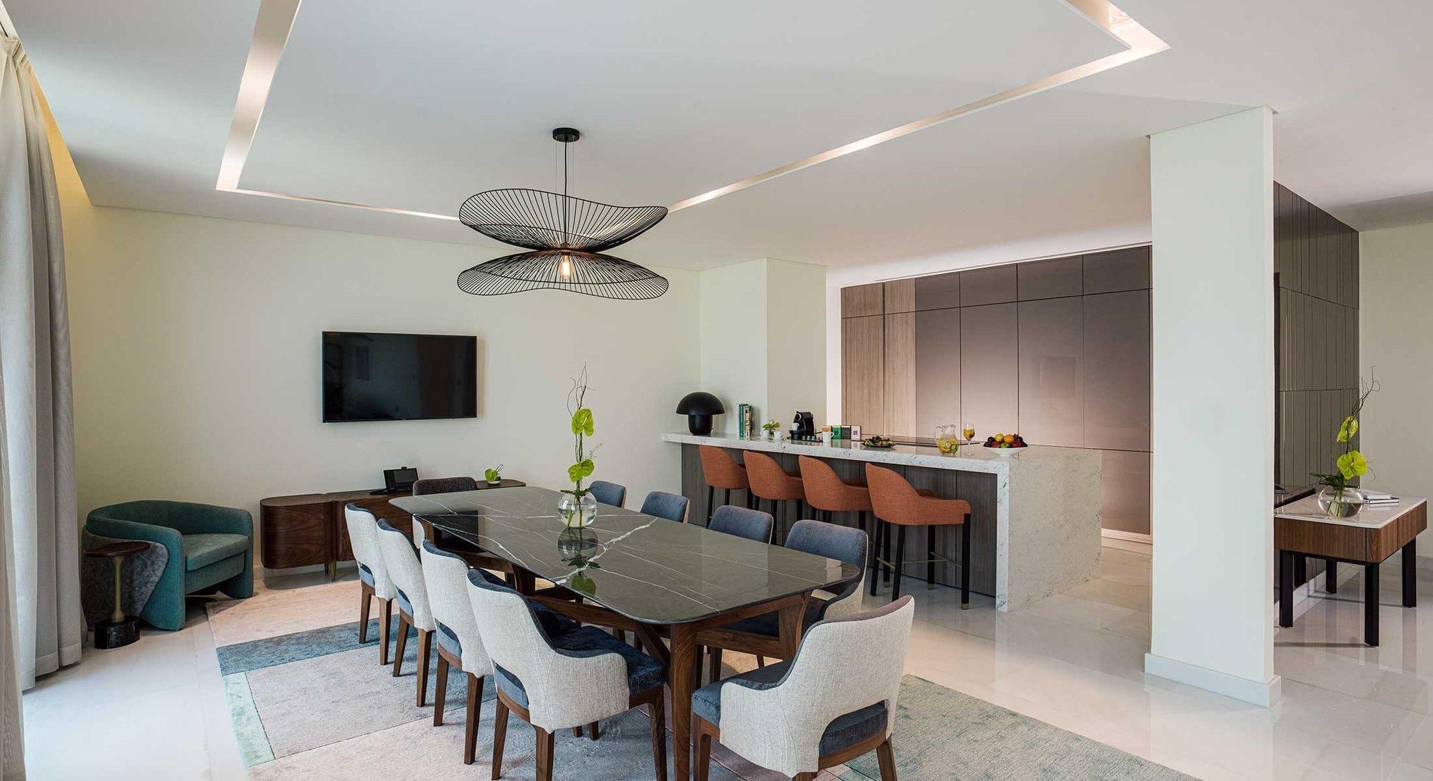 Un espace repas moderne avec une grande table, des chaises et un téléviseur.