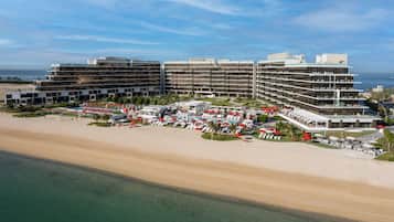 Een hotel aan het strand met meerdere verdiepingen, een zwembadgedeelte en uitzicht op het strand.
