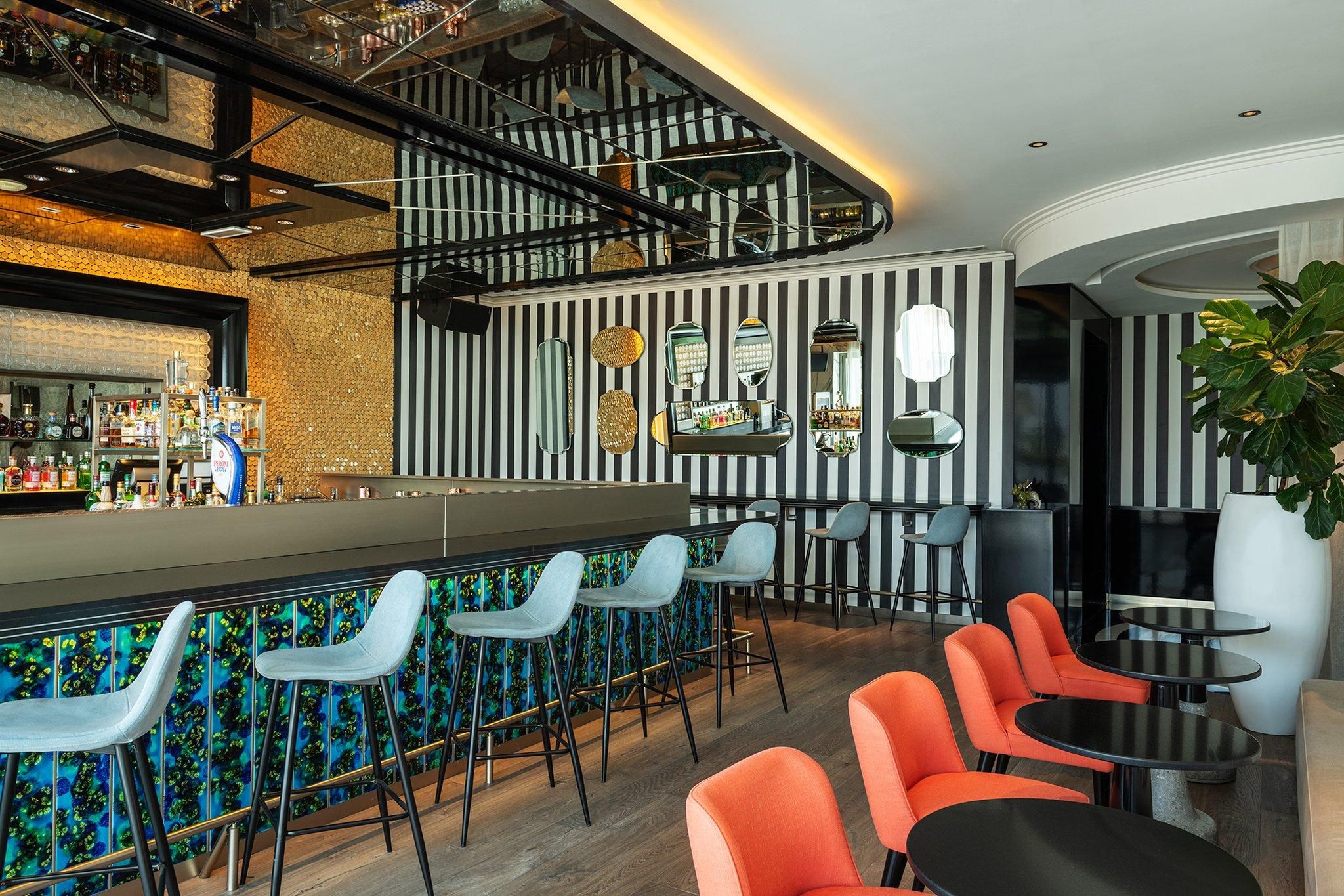 A bar area with a counter, bar stools, and seating with tables and chairs.