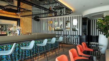 A bar area with a counter, bar stools, and seating with tables and chairs.