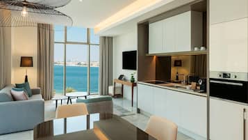 Een moderne hotelkamer met een zithoek, keuken en een groot raam met uitzicht op de stad.