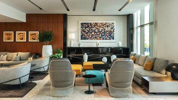 Un salon moderne avec un canapé, des fauteuils, une table basse et un grand tableau abstrait accroché au mur.