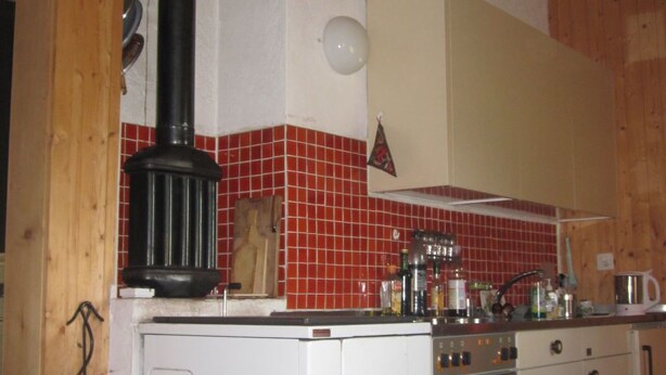 Una cocina con estufa, horno y una chimenea negra.