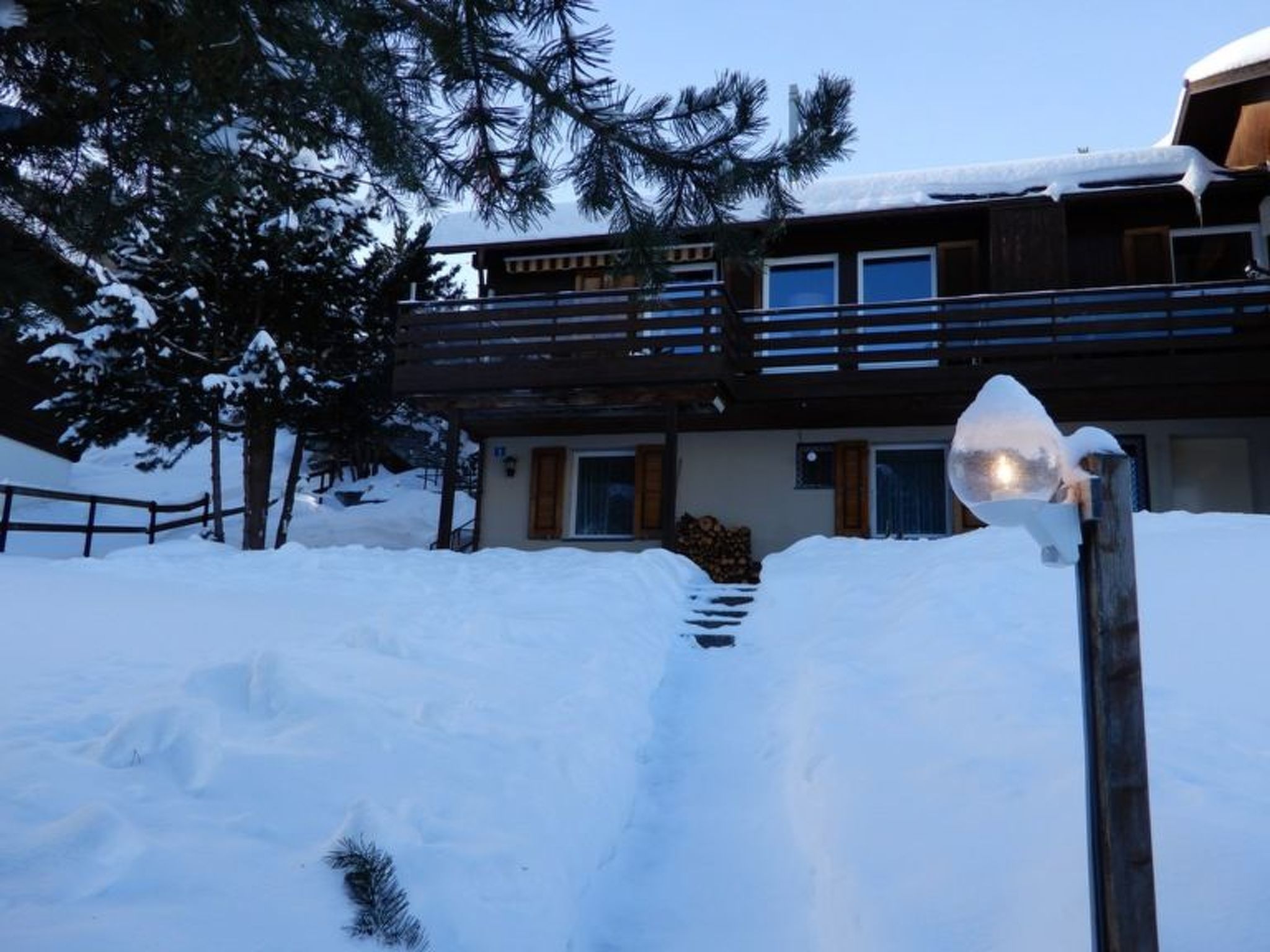 Un edificio de dos pisos con un balcón de madera y un paisaje cubierto de nieve.