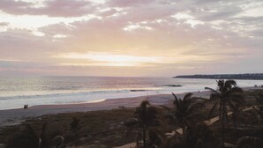 A beach with waves, palm trees, and a distant shoreline. - Lifestyle Hotel Juquilita - La Punta (Santa María Colotepec)