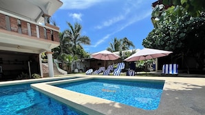 A swimming pool with lounge chairs and umbrellas, surrounded by a building with a staircase and greenery. - Lifestyle Hotel Juquilita - La Punta (Santa María Colotepec)