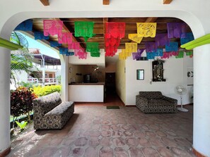 An interior with a reception desk, patterned sofas, and colorful hanging decorations. - Lifestyle Hotel Juquilita - La Punta (Santa María Colotepec)