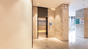 A modern elevator in a hallway with a textured wall and a marble floor. - Hanting Hotel Shenzhen Nanshan Avenue Branch (Shenzhen)