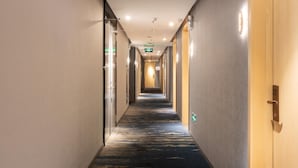 A hotel hallway with a carpeted floor, doors on both sides, and emergency exit signs. - Hanting Hotel Shenzhen Nanshan Avenue Branch (Shenzhen)