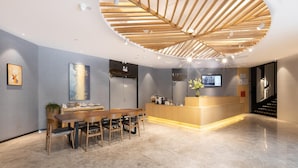 A modern reception area with a wooden reception desk, a seating area with chairs, and a large artwork on the wall. - Hanting Hotel Shenzhen Nanshan Avenue Branch (Shenzhen)