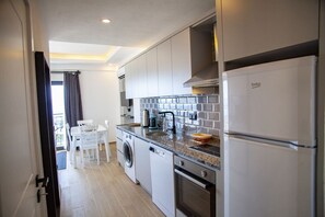 Una cocina compacta con lavadora, cafetera y refrigerador.